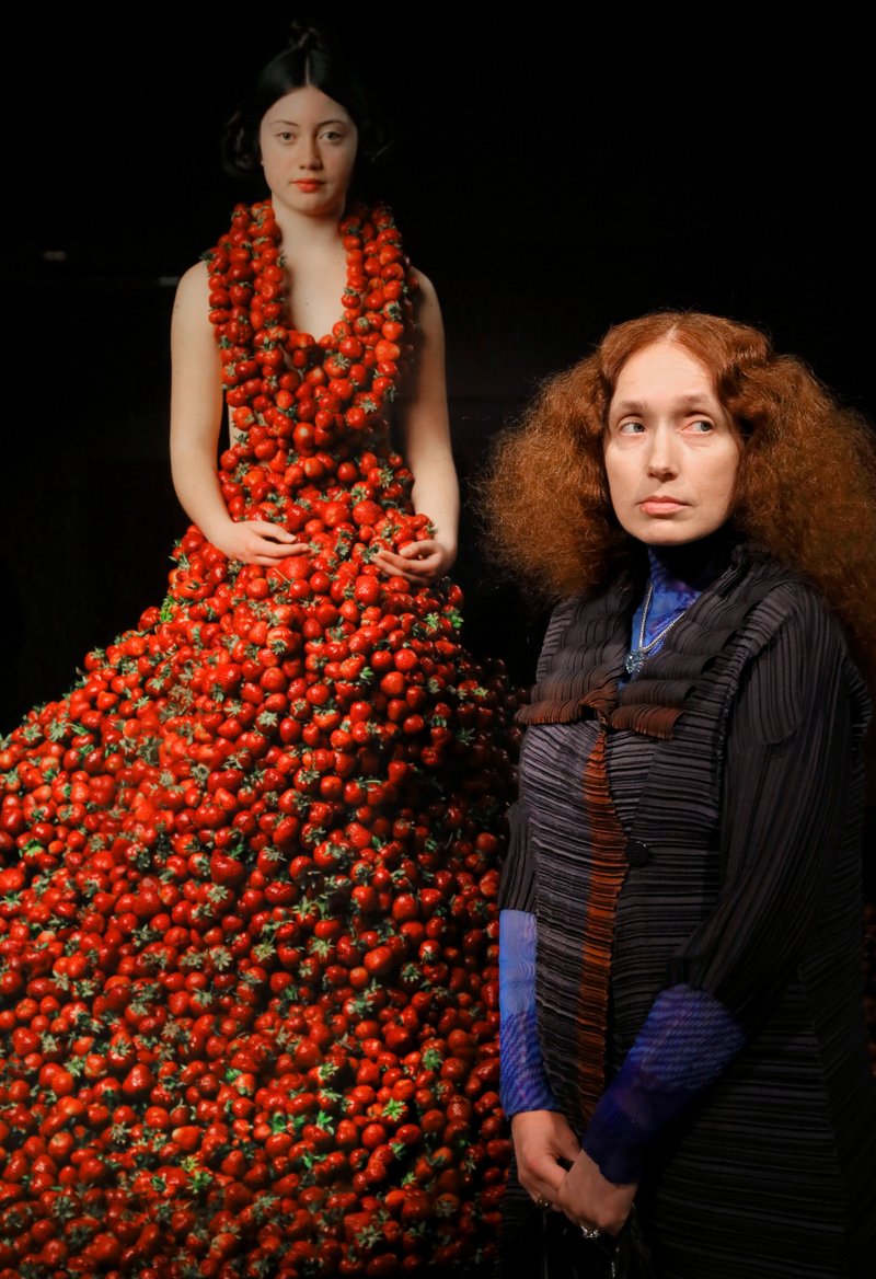 Photographer Nathalia Edenmont stands before Cousin Red, a model clad in many pounds of strawberries, in the atrium of the Arkansas Arts Center. “Nathalia Edenmont: Force of Nature,” 10 Edenmont prints, will be up through May 1.