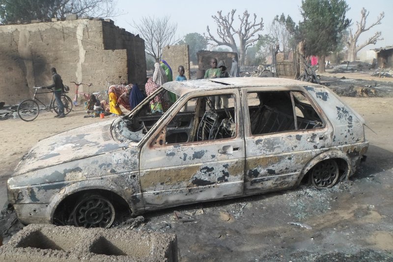 Children gather around a burned car on Sunday after an attack by Boko Haram in the village of Dalori, Nigeria.