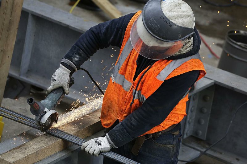 A worker cuts a steel bar at a construction site in New York on Monday. Construction spending edged up slightly in December, the Commerce Department said.