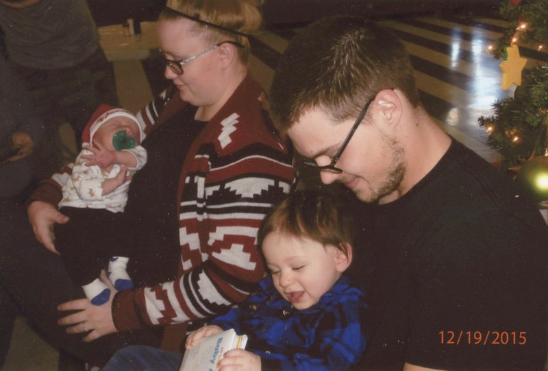 Photo by Snooky Garrett Risa Buckner, left, with her two-week-old son, Wesley Cupples, and Cody Payne, holding one-year-old son Ben, were among those enjoying the Payne family Christmas celebration Dec. 19 at the Gravette Civic Center. Young Ben was having an especially good time since he spent his first Christmas in NICU.