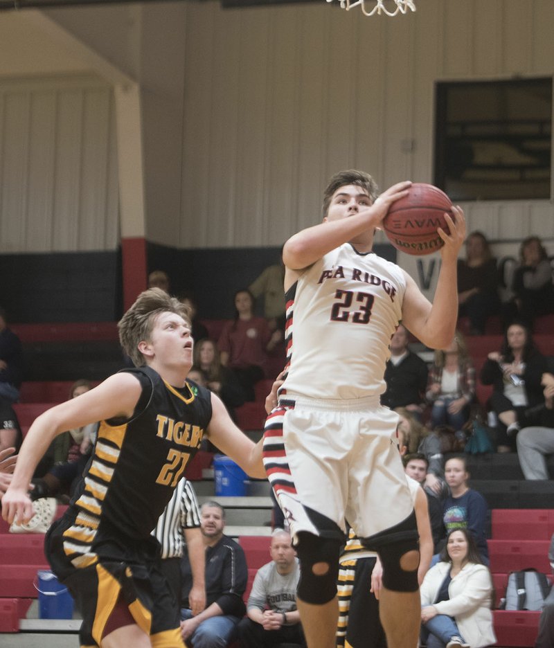 Pea Ridge’s Britton Caudill shoots Tuesday while Prairie Grove’s Nick Ellis defends in Pea Ridge. For a gallery of game images, go to nwamedia.photoshelter.com.