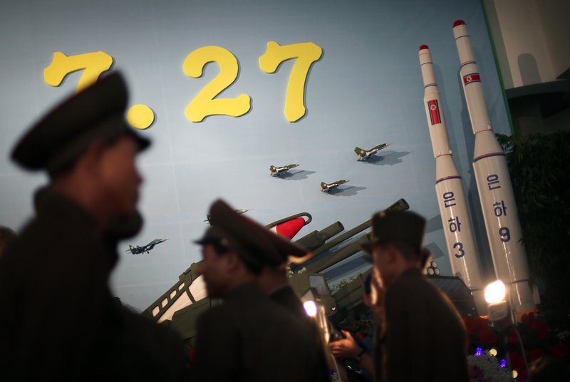 In this July 26, 2013, photo, North Korean soldiers are silhouetted against model versions of the Unha 3 space launch vehicle which successfully delivered North Koreas first satellite into Earth orbit, and the Unha 9, right, which would carry a lunar orbiter, on display at an annual flower show held in honor of national founder Kim Il Sung and his son Kim Jong Il, in Pyongyang, North Korea. 