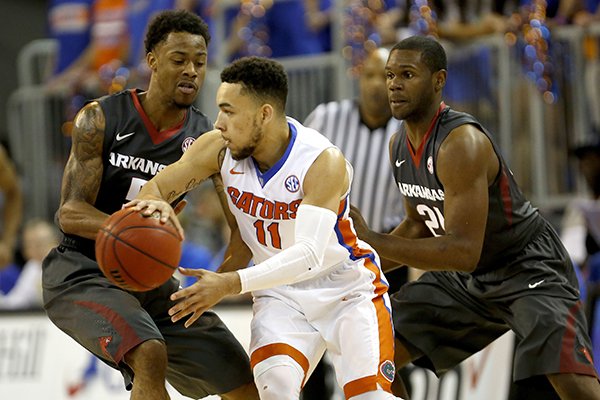 Florida guard Chris Chiozza (11) looks to pass around full-court pressure by Arkansas guard Anthlon Bell (5) and guard Manuale Watkins (21) during the first half of an NCAA college basketball game at the O'Connell Center on Wednesday, Feb. 3, 2016 in Gainesville, Fla. (Matt Stamey/The Gainesville Sun via AP)