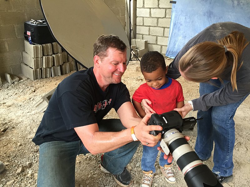 Tony Thurman, left, shows a child his school picture. Thurman spent time building a school and connecting with the community in Constanza, Dominican Republic, as part of a Lifetouch Memory Mission.