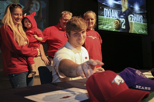 Little Rock Christian's Dylan Hays reaches for an Arkansas hat Wednesday after signing to play football at Arkansas during a ceremony at the school.