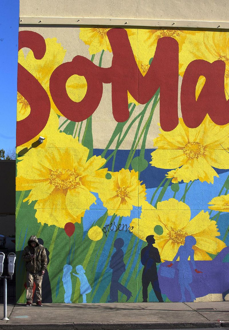 A man who gave his name only as Braden R. stands Wednesday in front of a mural in the Little Rock district known as SoMa on South Main Street.