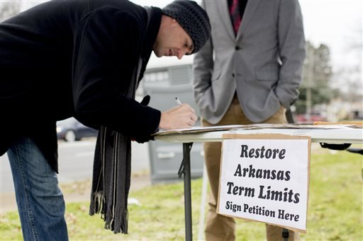 In this Jan. 18, 2016 photo, Stuart Rubio, left, signs a petition to limit lawmakers terms before the Martin Luther King Jr. Day parade in Little Rock.