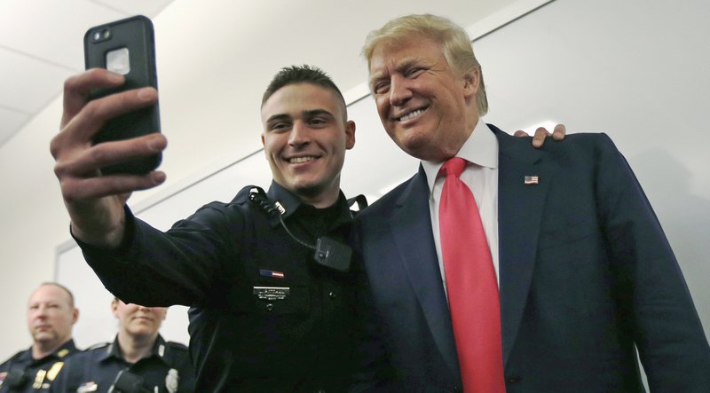 Patrolman James Pittman poses for a selfie with Republican presidential candidate Donald Trump during a campaign stop at police headquarters in Manchester, N.H., Thursday, Feb. 4, 2016. 