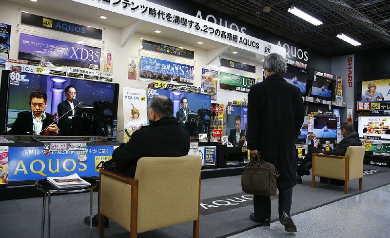 Shoppers look at Sharp’s Aquos flat-panel TVs at an electronics store in Tokyo on Thursday. 