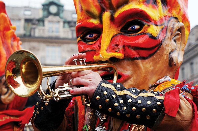 A party-animal in a papier-mache mask celebrates Carnival in Lucerne, Switzerland, with her trumpet. 