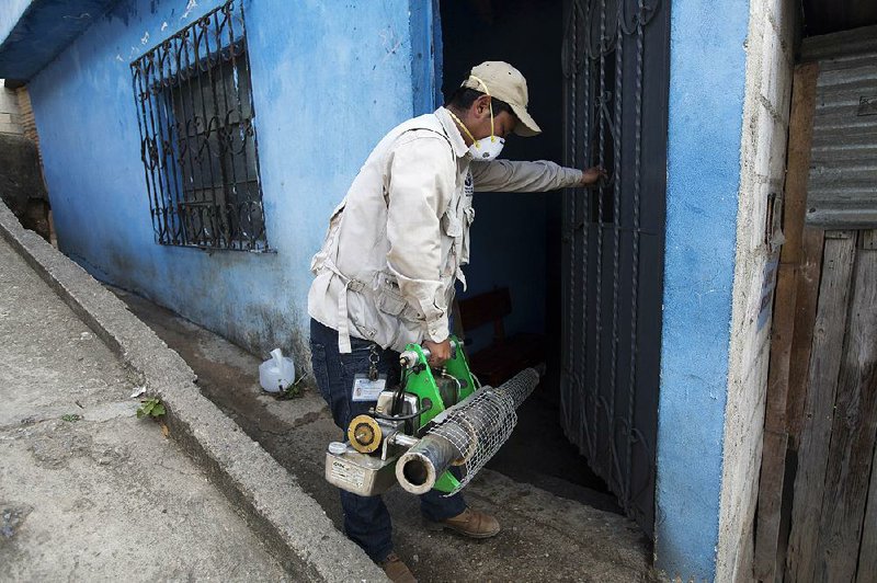 A Health Ministry worker sprays insecticide Friday around a neighborhood in Guatemala City.