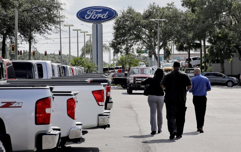 A salesman walks customers through the inventory in the used-car lot at Brandon Ford in Brandon, Fla., in this file photo. The Federal Reserve said consumer borrowing increased $21.3 billion in December.