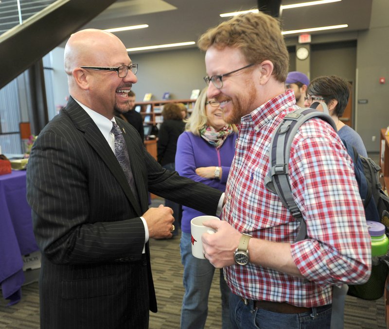 Matthew Wendt (left), newly hired superintendent of Fayetteville Schools, laughs Friday with Clay Morton, a science teacher at Fayetteville High School, during a reception in the school’s library.
