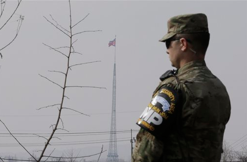 A North Korean flag flies in Gijungdong as a U.S. Army soldier stands guard at Taesungdong near the border of Panmunjom in Paju, South Korea, on Thursday, Feb. 4, 2016. South Korea and Japan vowed to shoot down any debris that falls on their territories from a long-range rocket that North Korea plans to fire this month.
