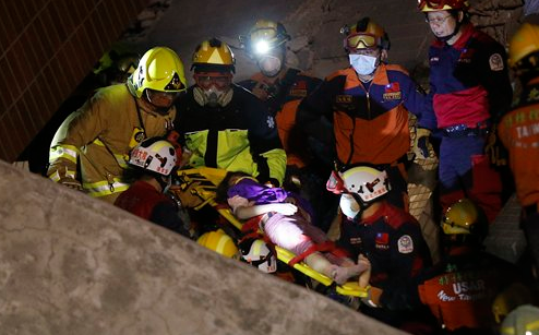 A woman is rescued from a collapsed building complex after an early morning earthquake in Tainan, Taiwan, on Saturday, Feb. 6, 2016. At least one high-rise residential building toppled and trapped people inside.