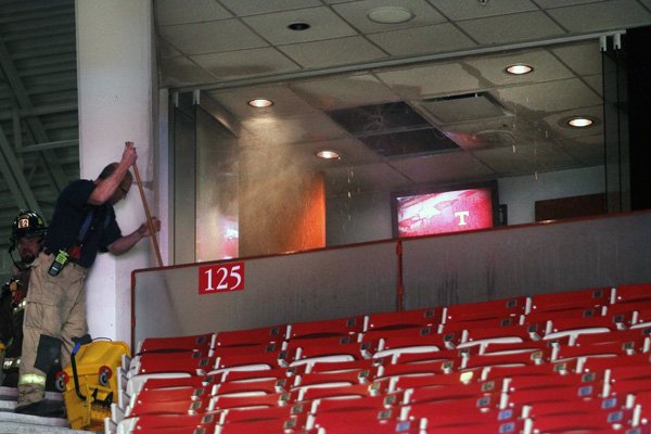 Water pours out of the fire sprinklers in a suite-level box at Bud Walton Arena, Saturday, Feb. 6, 2016, in Fayetteville, Ark., as a firefighter attempts to clean up the water spilling into the stands. The fire sprinklers turned on after a small fire started in the suite box. The incident did not cause a delay in the start of the NCAA college basketball game between Tennessee and Arkansas. (AP Photo/Samantha Baker)
