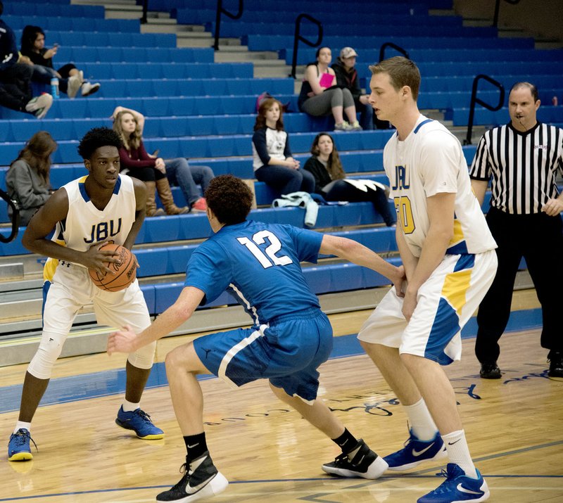 Photo courtesy of JBU Sports Information John Brown University freshman Marquis Waller holds the ball as freshman Ben Smith, right, sets a screen on Southwestern Christian&#8217;s Mikel Parish during Thursday&#8217;s game at Bill George Arena. Parish scored with two seconds remaining to give Southwestern Christian a 61-59 victory.