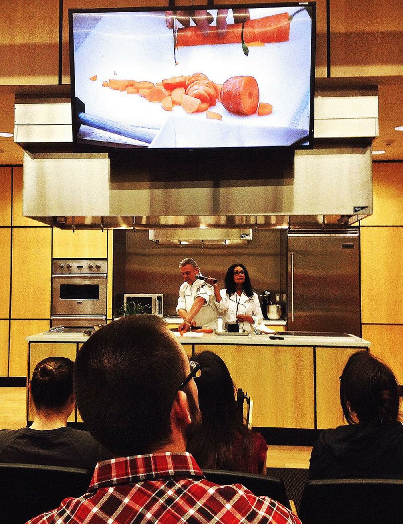 Members of the UAMS Integrative Medicine Interest Group watch as Chef Philippe Ducrot shows them how not to chop their fingers off while Dr. Meenakshi Budhraja holds the mic. 