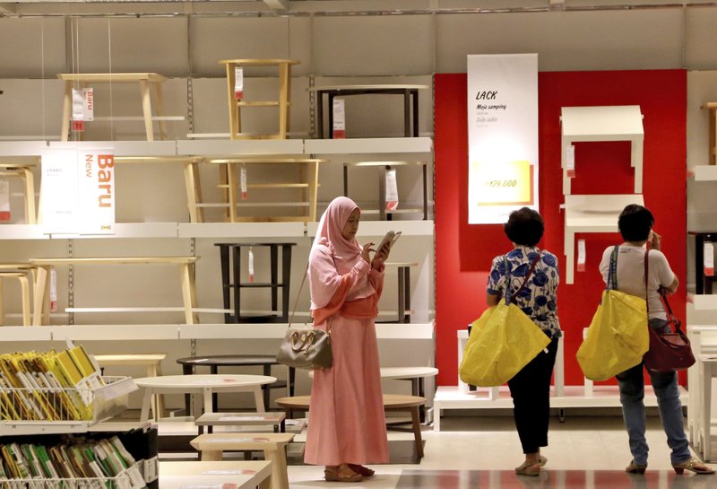 A Muslim woman checks her mobile phone as two shoppers stand by at the IKEA store in Tangerang, Indonesia, Friday, Feb. 5, 2016. The furniture giant, founded in Sweden in 1943, has lost a trademark dispute in Indonesia after the country's highest court agreed the IKEA name was owned by a local company.