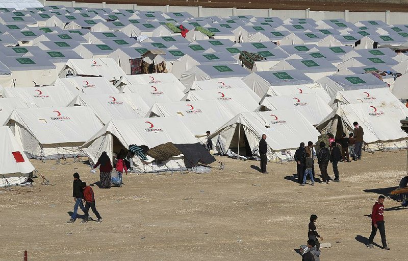 Displaced Syrians walk Monday through a temporary refugee camp in northern Syria, near the border with Turkey.