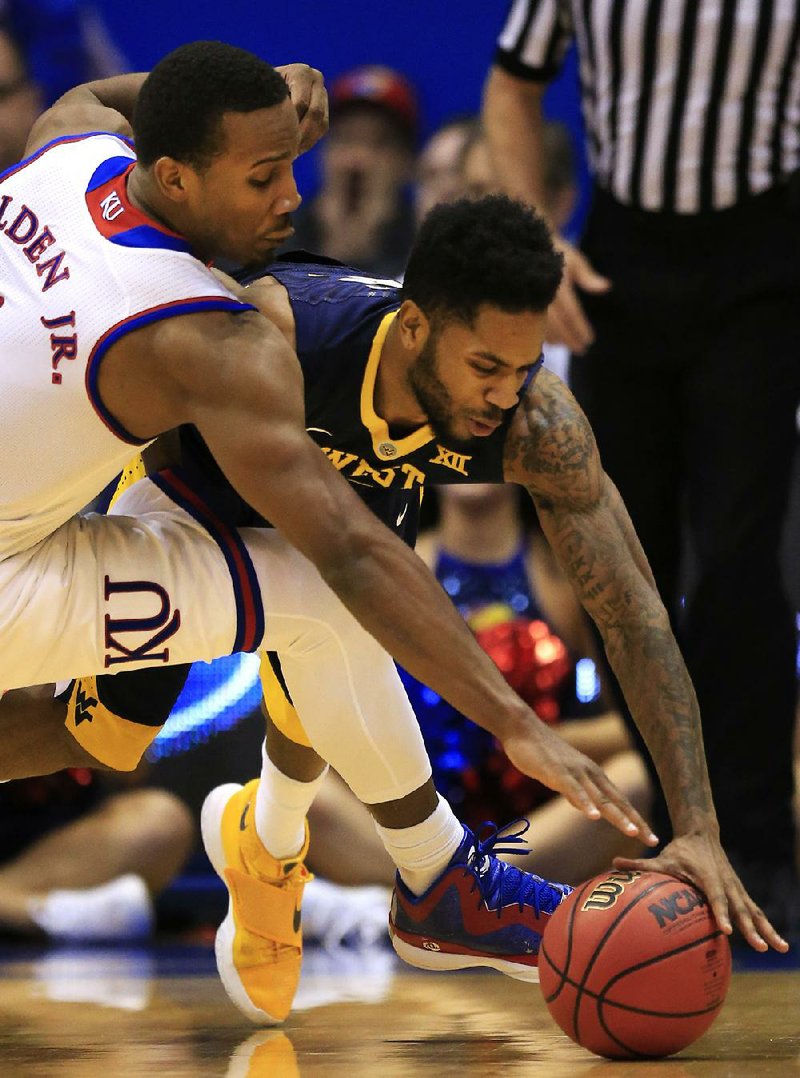 Kansas guard Wayne Selden Jr. (left) and West Virginia’s Tarik Phillip fight for a loose ball during Tuesday night’s game in Lawrence, Kan.