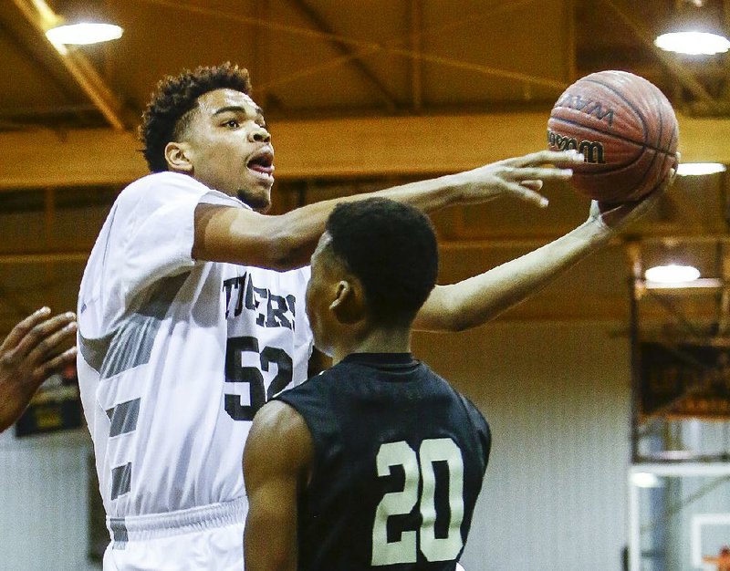 Little Rock Central center Raekwon Rogers (52) tries to put up a shot in front of Jonesboro’s Jonathan Adams in the Tigers’ 78-68 loss to the Hurricane in a 7A/6A-East game Tuesday in Little Rock.