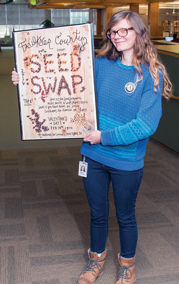 Kim Doughty, Arkansas GardenCorps service member, holds a sign advertising the Seed Swap, a project of the Faulkner County Library and the Faulkner County Urban Farm Project, both in Conway. The annual event will be held from 1-4 p.m. Sunday at the library, 1900 Tyler St. People may bring seeds to share, but they don’t have to have seeds to participate, Doughty said.