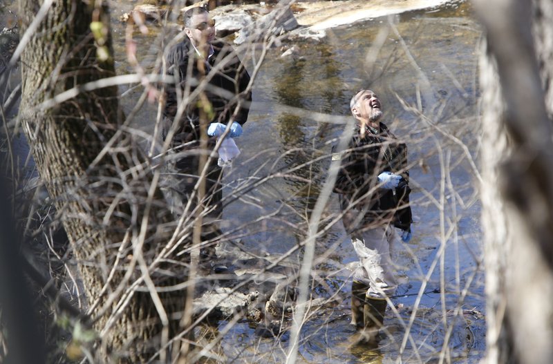 John Brooks, a crime scene investigator with Fayetteville’s Police Department, collects evidence Wednesday at Clear Creek on the north side of the Razorback Greenway near the Northwest Arkansas Mall in Fayetteville. The body of a deceased white male was found in the creek. 