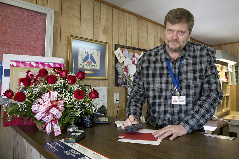 Postmaster John David Parham stamps a letter with the specialized Romance handstamp, only available at the Romance post office.