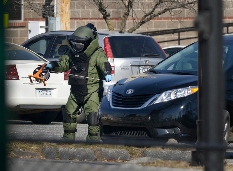 A member of Bentonville’s Bomb Squad investigates a suspicious package Thursday in the parking lot south of the Benton County Courthouse and Administration Building in Bentonville. Police determined a backpack placed under a black van wasn’t hazardous.