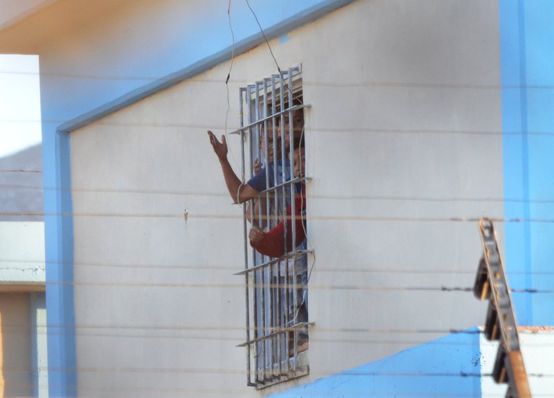 Inmates shout from a barred window at the Topo Chico prison, after a riot broke out around midnight, in Monterrey, Mexico, Thursday, Feb. 11, 2016. Dozens of inmates were killed and several injured in a brutal fight between two rival factions at a prison in northern Mexico on Thursday, the state governor said.