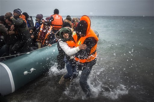 In this Sunday, Jan. 3, 2016, file photo, refugees and migrants disembark on a beach after crossing a part of the Aegean sea from Turkey to the Greek island of Lesbos.