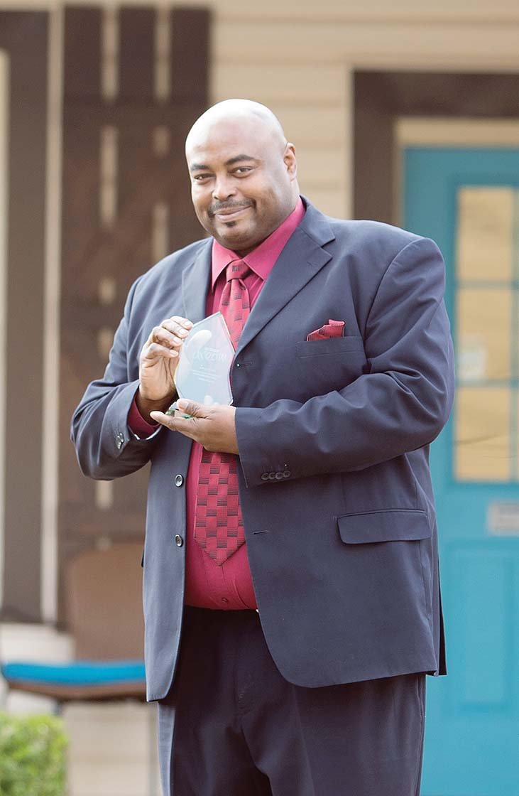 Dwight McCullough holds his Dare to Dream Award in front of the Deliver Hope Resource Center on Robinson Avenue in Conway. McCullough, a Faulkner County juvenile probation officer, is the first recipient of the award, given by the nonprofit organization for at-risk youth. McCullough said his job is to help young people succeed, not judge them.