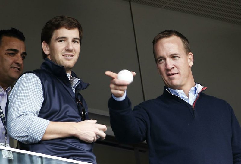 In this May 4, 2014, file photo, Denver Broncos quarterback Peyton Manning, right, points out something in the stadium to his brother, New York Giants quarterback Eli Manning.