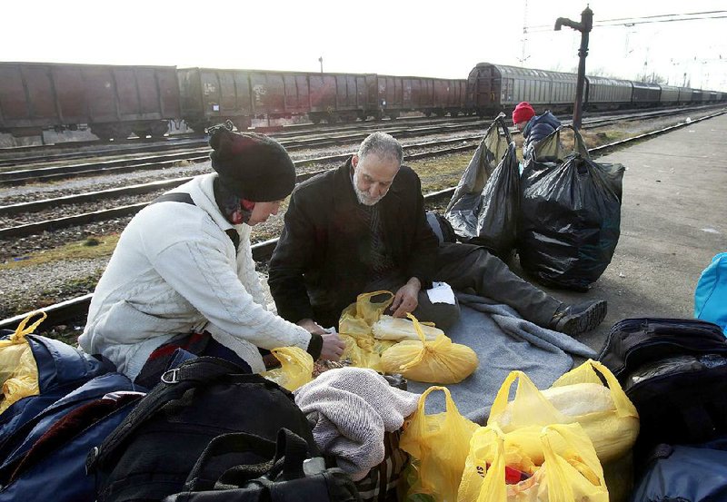 A Syrian couple heading to Serbia has a meal and rests after arriving Friday at a transit center for refugees near the northern Macedonian village of Tabanovce.