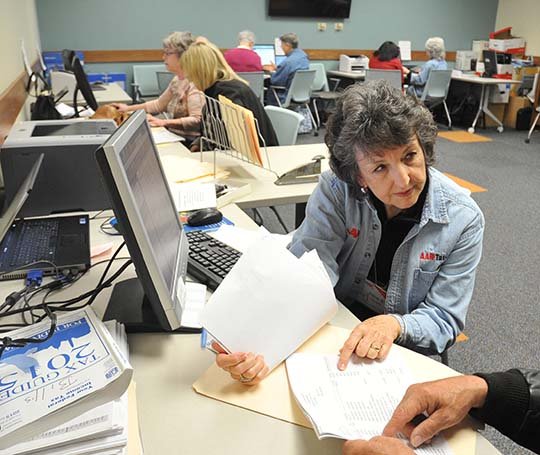 The Sentinel-Record/Mara Kuhn TAX PREP: Irene Sandhaus, an AARP tax aide volunteer, helps a couple with their annual income tax at the Garland County Library on Thursday.