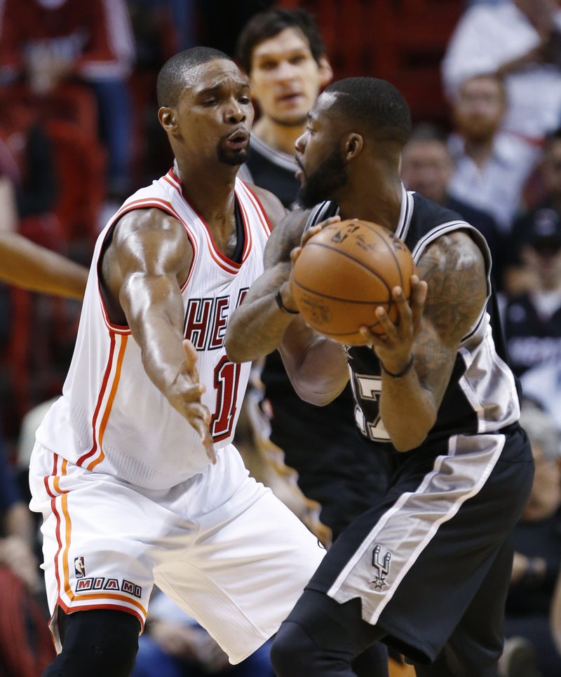 San Antonio Spurs guard Jonathon Simmons (17) looks for an opening past Miami Heat forward Chris Bosh (1) during the first half of an NBA basketball game, Tuesday, Feb. 9, 2016, in Miami.