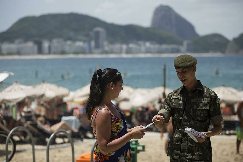 A soldier on the Copacabana beach in Rio de Janeiro explains Saturday how to combat the mosquito that spreads the Zika virus. 