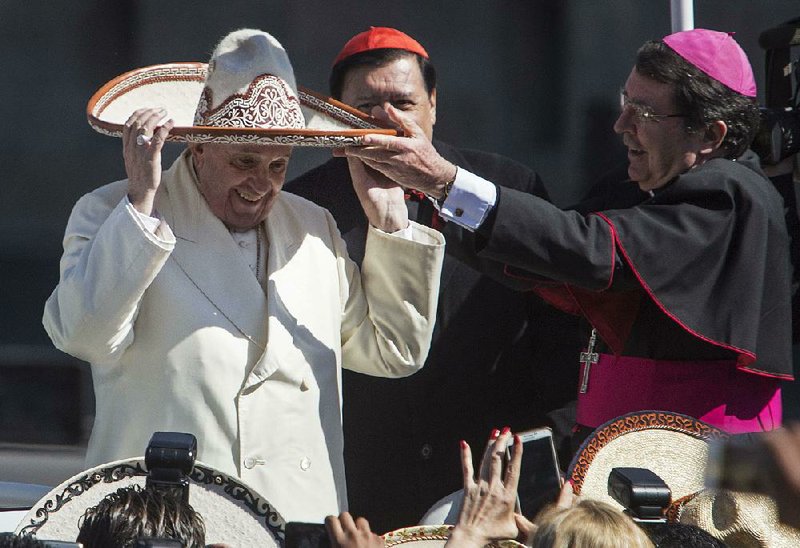 Accompanied by Mexican Cardinal and Archbishop of Mexico City Norberto Rivera and Papal Nuncio Christophe Pierre, Pope Francis tries on a sombrero given to him by a person in the crowd Saturday, Feb. 13, 2016, in Mexico City. 
