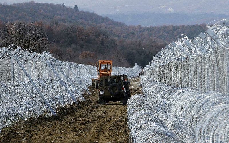 Macedonian army vehicles move along a path between lines of fence reinforced with razor wire on the border with Greece near the southern Macedonia town of Gevgelija on Sunday.