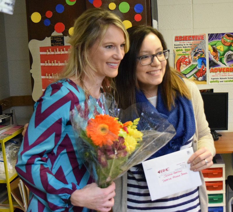 Photo by Mike Eckels Jessica Hartman (right) receives an award from Sarah Day, with BHC Insurance, in her classroom at Decatur Middle School on Feb. 2. Hartman, a sixth-grade science and English teacher, received the award for her dedication to her students and fellow teachers.