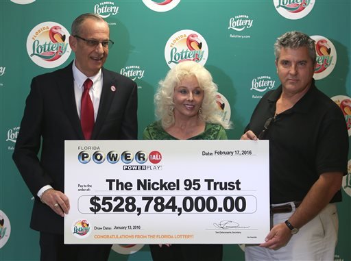 Florida Lottery Secretary Tom Delacenserie, left, presents Maureen Smith and David Kaltschmidt with their one-third share of the Jan. 13, world record Powerball jackpot Wednesday, Feb. 17, 2016, in Tallahassee, Fla.
