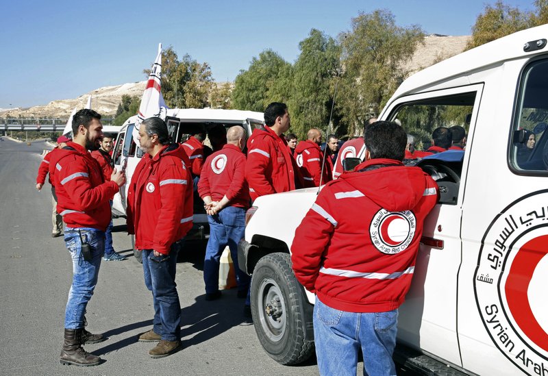 Staff from the Syrian Arab Red Crescent get ready to accompany a convoy of humanitarian aid as it waits in front of the United Nations Relief and Works Agency (UNRWA) offices before making their way into the government besieged rebel-held towns of Madaya, al-Zabadani and al-Moadhamiya in the Damascus countryside, as part of a U.N.-sponsored aid operation, in Damascus, Syria, Wednesday, Feb. 17, 2016. 