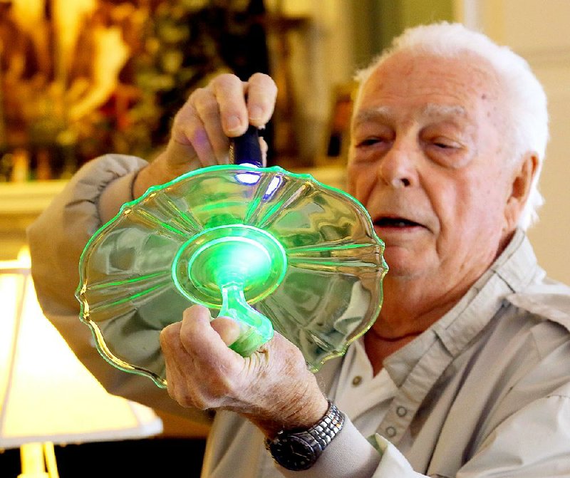 The uranium in a Vaseline Depression-era glass dish glows green as Bud Martin hits it with a beam of ultraviolet light. Martin is chairman of the Arkansas Glasshoppers’ Depression Era and Vintage Glass Show and Sale on Saturday and Feb. 28 at the State Fairgrounds. 