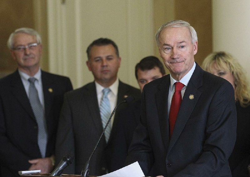 Gov. Asa Hutchinson tells more than 20 legislators and officials at a press conference Tuesday that supporting Arkansas Works is not the same as supporting the Affordable Care Act. 