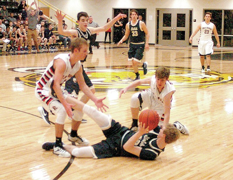 Photo by Mike Capshaw Blackhawk junior Joey Hall, left, and sophomore Hayden Holtgrewe try to corral Shiloh Christian&#8217;s Kyle Tune after Tune dove to the floor for a loose ball during the Blackhawks&#8217; 61-51 win in the semifinals of the 4A-1 District Tournament in Prairie Grove Friday.