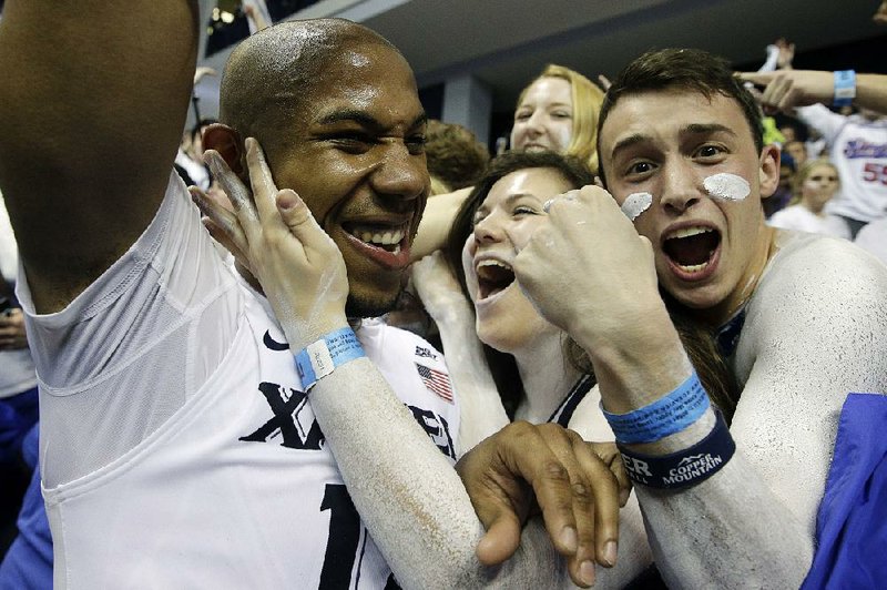 Xavier’s Myles Davis (left) celebrates with fans after the No. 5 Musketeers’ victory over top-ranked Villanova on Wednesday night in Cincinnati.