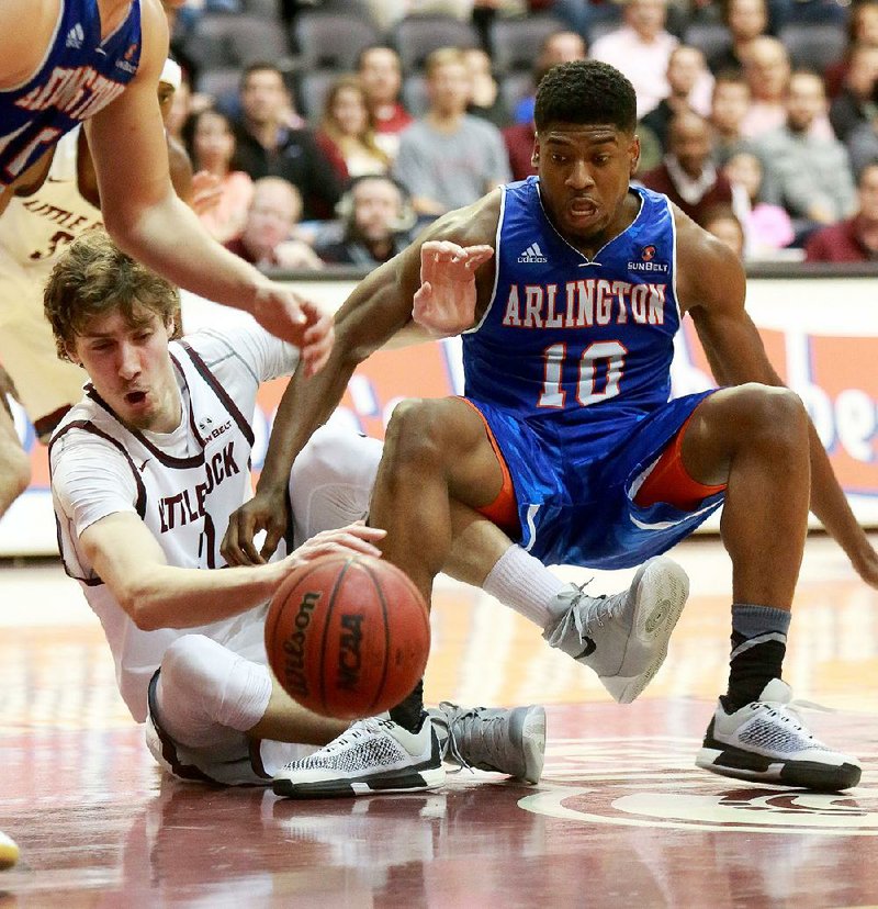 UALR’s Lis Shoshi (left) and Texas-Arlington’s Jalen Jones battle for a loose ball during Thursday night’s game at the Jack Stephens Center in Little Rock. Shoshi scored 13 points as the Trojans clinched at least a share of the Sun Belt Conference regular-season title with a 72-60 victory in front of an announced sellout crowd of 5,253.