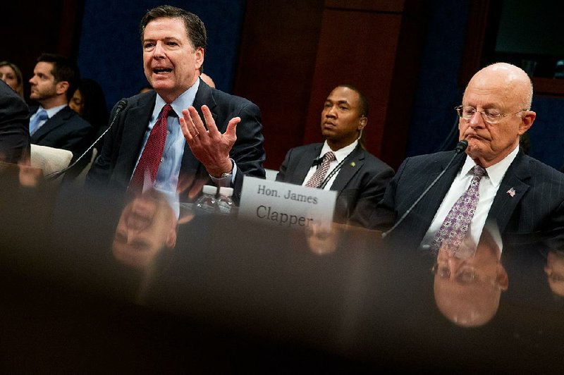 FBI Director James Comey, left, accompanied by Director of National Intelligence James Clapper, right, speaks at a House Intelligence Committee hearing on world wide threats on Capitol Hill in Washington, Thursday, Feb. 25, 2016.  