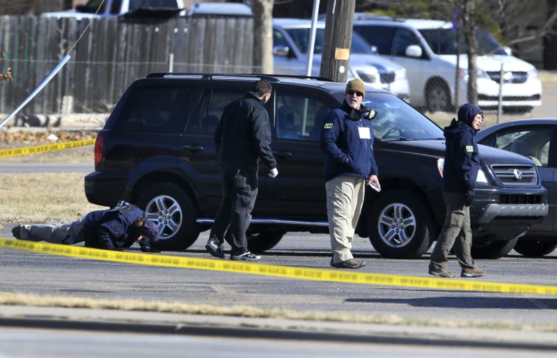 FBI agents search the parking lot Friday at Excel Industries in Hesston, Kan., as they investigate Thursday’s shootings.